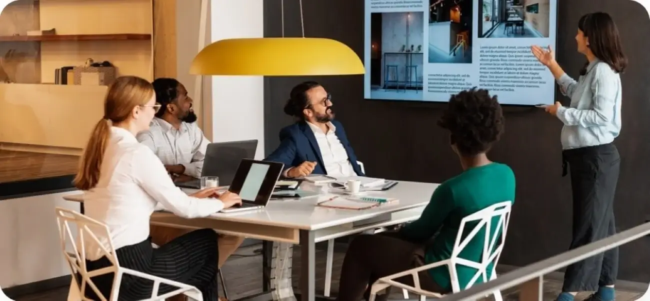 A group of business professionals seated around a conference table, discussing a detailed business plan document.